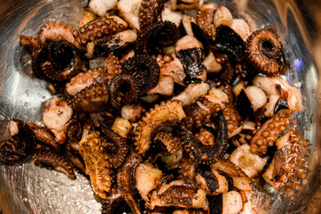 Close-up view on parts of small octopuses in metal bowl.