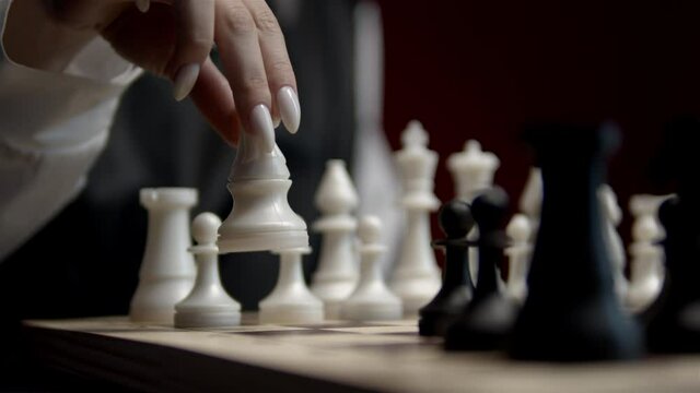 Chess game. Pawn. Female hand. By sacrificing a pawn. Queen. Policy and strategy. Black and white. White nails and white chess. Start of the game.  Close-up.