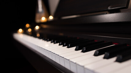 Fototapeta na wymiar Piano keyboard close up and blurred candle light background