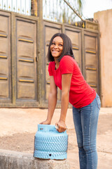 happy nigerian woman going to buy gas in her gas cylinder