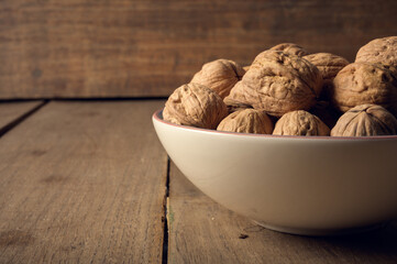Walnuts in a ceramic bowl on a dark wooden background