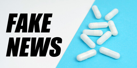 There are pills on the blue surface, on the white surface it says - FAKE NEWS