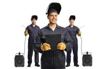 Welders holding a clipboard and standing in front of other welders with welding machines