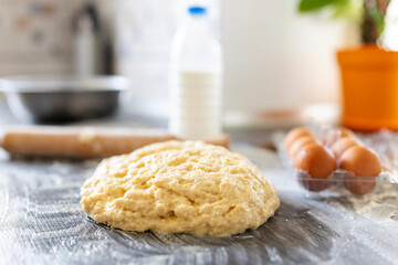 Homemade dough, rolling pin and baking ingredients on a dark wooden table in kitchen. Preparation of the dough