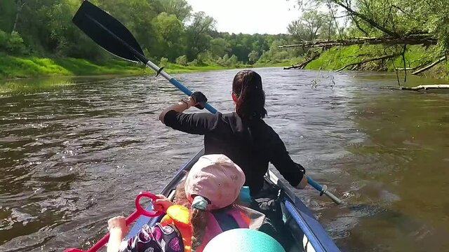 Family kayak trip. Mom and daughter rowing a boat on the river, a water hike, a summer adventure. Eco-friendly and extreme tourism, active and healthy lifestyle