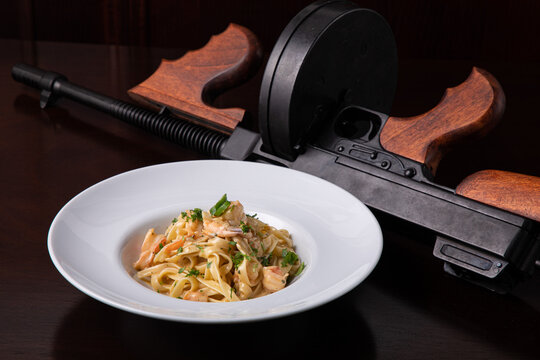 Thompson submachine gun and Italian pasta with prawns chili pepper and greens