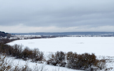 Fototapeta na wymiar View of the Oka River in winter. Snowy landscapes of the Russian hinterland. Snow-covered landscapes with views of the river and fields.