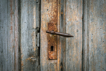 Antique rusty doorknob on an ancient wooden door of an old farm barn