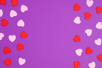 Creative layout with pink and red hearts on purple background. Flat lay. Minimal love concept.