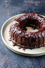 Traditional chocolate bundt cake with icing glaze topping and muscovado brown sugar served as close-up on a plate with copy space