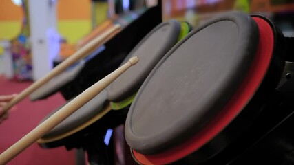 Close up: woman gamer hands using drum sticks joystick and playing rhythm drum arcade machine at retro arcade hall. Hobby, percussion and leisure time concept