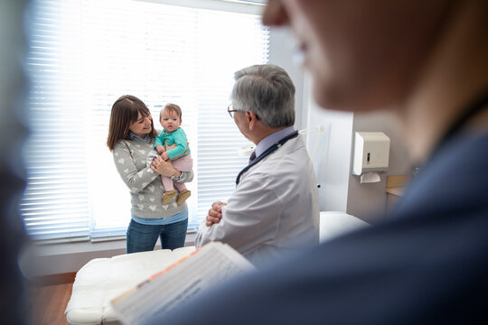 Pediatrician with baby and mother in examination room
