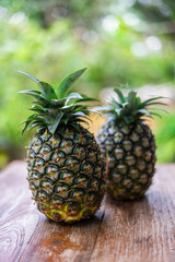 Whole pineapple on the wooden table with garden blackground.