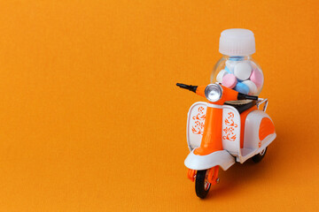 Toy motorbike delivering a bottle of pills. Online delivery of  medicines concept
