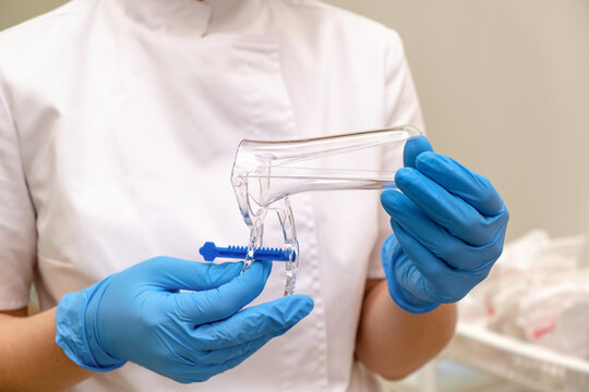 Gynecologist in blue medical gloves holding vaginal speculum in his hands closeup.Women's health, medical concept.