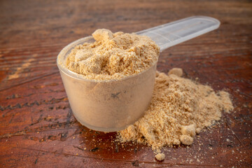 measuring scoop of maca root  powder - top view against painted wood background