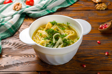 Chicken soup bouillon in a plate on wooden table