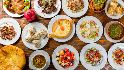 Georgian cuisine foodset from khachapuri, khinkali, pkhali, dolma, satsivi , ajara khachapuri, salad caesar with chicken, fried khinkali, top view on wooden table