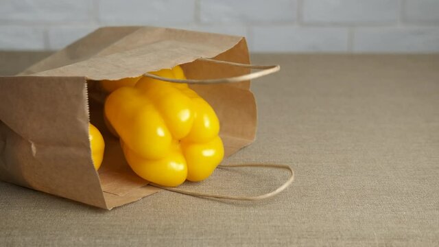 Ripe peppers in a bag. A woman takes out the pappers from the craft bag on the table.