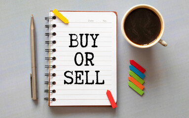 BUY OR SELL entry in a white notebook and a cup of coffee