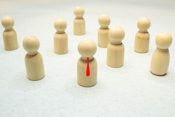 Small group of separated people seen from above represented anonymous with wooden figures on white background