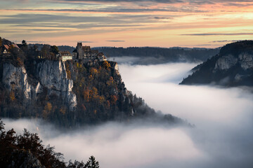 castle above fog in a valley during sunrise