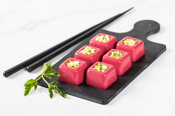Beetroot cream jelly in the form of small portions of a square shape with a filling of finely chopped egg with parsley on a serving board on a white background