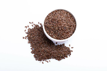 Flax seeds in a white ceramic cup on a white background.