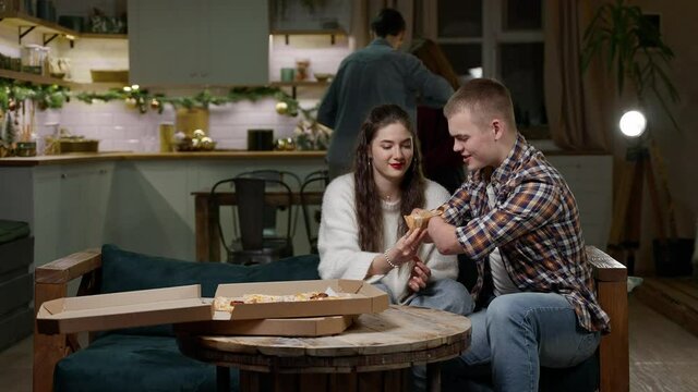 Youth home non-alcoholic pizza party. A guy with a disability with amputated hands has fun with friends in the living room of the studio apartment