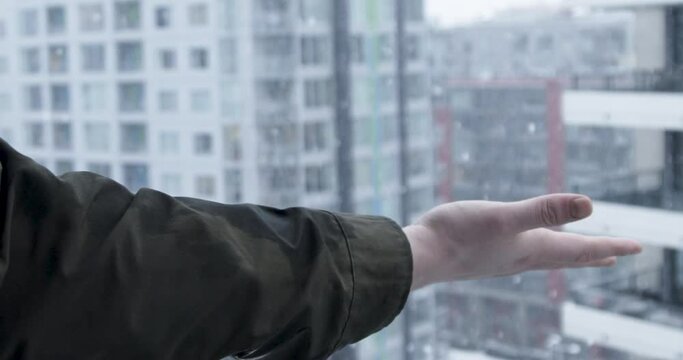 Slow-motion stock footage of a man enjoys the snow from his apartment balcony during a snowfall blizzard in Vancouver, Canada