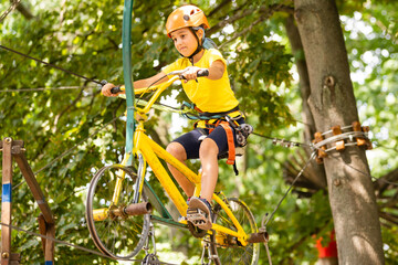 Adorable little girl enjoying her time in climbing adventure park on warm and sunny summer day