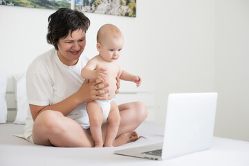 Mom and baby looking at a laptop and smiling happy.