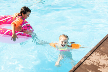 Happy children in the swimming pool. Funny kids playing outdoors. Summer vacation concept.