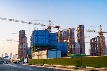 Obraz premium Silhouettes of tower cranes against the evening sky. House under construction. Industrial skyline