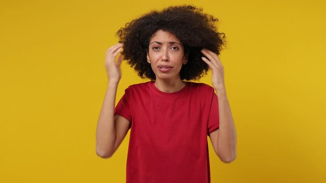 Sad upset worried disturb displeased young black woman 20s wears red t-shirt sigh suspire sithe put hands on face isolated on plain yellow background studio portrait. People emotions lifestyle concept