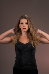 Retrato de mulher loira de olhos verdes, cabelo cacheado em fundo cor salmão no estúdio. Jovem...