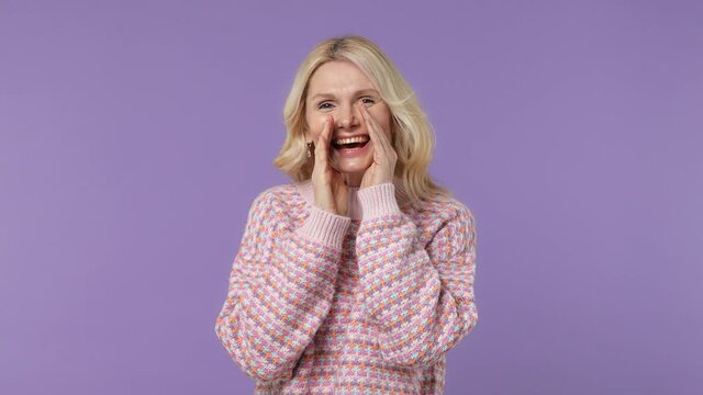 Vivid charismatic elderly blonde woman lady 40s years old wears warm shirt scream hot news about sales discount with hands near mouth isolated on plain pastel light purple background studio portrait