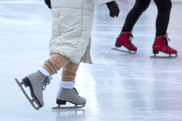 Obraz premium Ice skating on an ice rink. legs with skates. Winter active sport and leisure hobby.