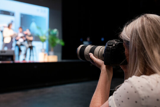 Female photographer with digital camera at presentation