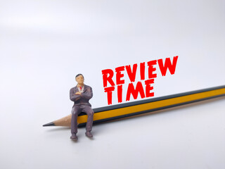 Miniature people and pencil with text REVIEW TIME on white background.