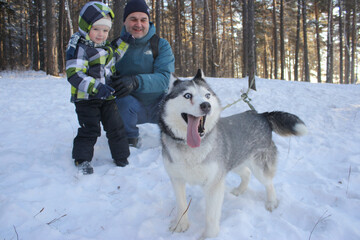 Pets happy husky dog father and son walk in the winter forest