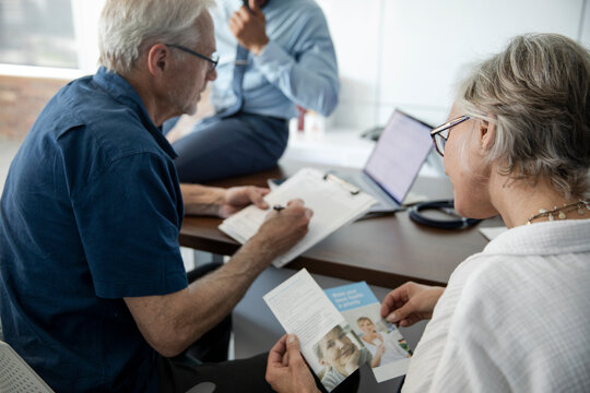 Senior couple discussing medical insurance with doctor