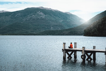 Mujer sentada en soledad en el muelle de un lago patagónico, en Bariloche, Argentina