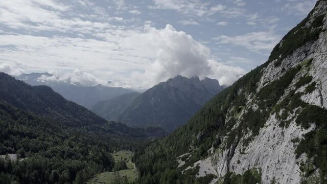 Drone video with diagonal plane over the Vrsc pass in Slovenia with mountains on the horizon.