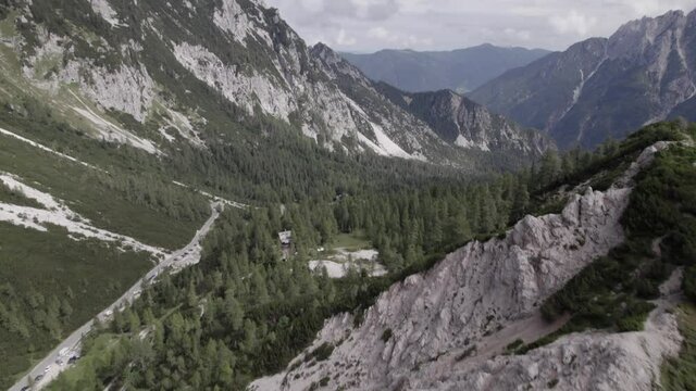Drone video with descriptive frontal shot over the Vrsc pass in Slovenia with mountains on the horizon.