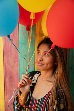 Playful young woman with balloons on summer patio
