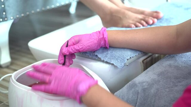 Beautiful Asian young woman having a paraffin foots and hands spa at beauty - spa shop. Foot and hand paraffin treatment.