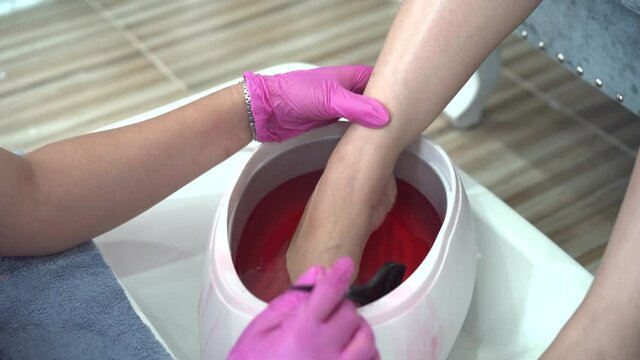 Beautiful Asian young woman having a paraffin foots and hands spa at beauty - spa shop. Foot and hand paraffin treatment.