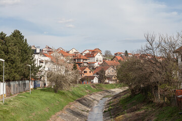 Fototapeta na wymiar Panorama of Resnik district, with the river topciderska reka passing by a typical suburban settlement with individual residential houses. Resnik is a district of Belgrade in Rakovica municipality...