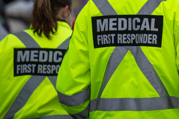 Medical first responders walking along a road wearing black wool stocking caps, yellow reflective...